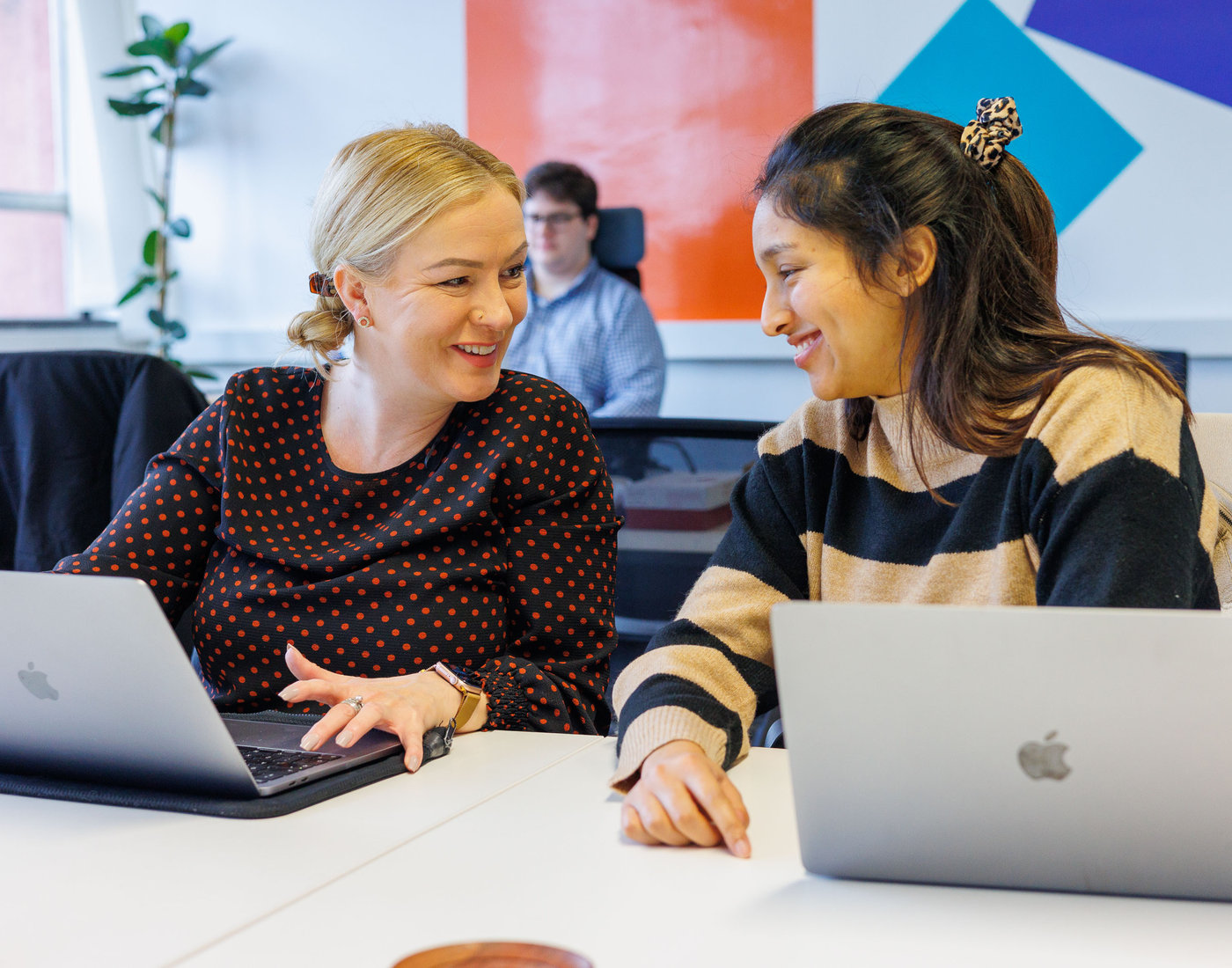 Two Boulevard colleagues smiling while working together on laptops